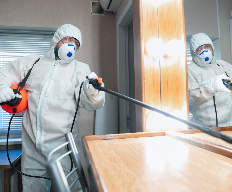 Coronavirus Pandemic. A disinfector in a protective suit and mask sprays disinfectants in house or office. Protection against COVID-19 disease. Prevention of spreding pneumonia virus with surfaces.